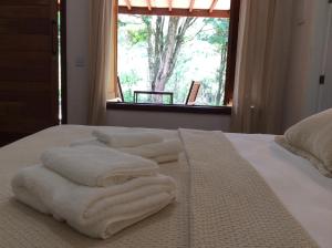a white towel laying on top of a bed next to a window at Villa Domaso in Brumadinho