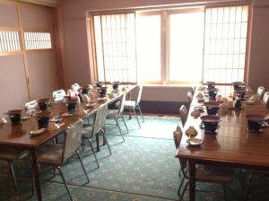 Habitación grande con mesas y sillas de madera. en Hotel & Onsen 2307 Shigakogen, en Yamanouchi