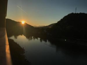 a sunset over a river with the sun setting at Apart & Hostel Konjic in Konjic