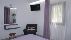 シヴォタにあるSivota Coloursの壁にテレビと椅子が備わるベッドルーム1室