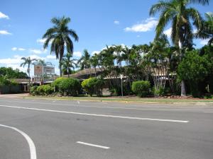 an empty street with palm trees and a building at Cattleman's Rest Motor Inn in Charters Towers