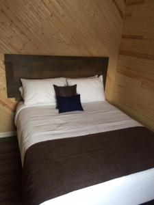 a large bed with a blue pillow on it at The Southern Port Hotel & Chalets in Harbour Breton