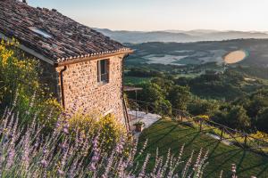 una casa de piedra en una colina con un campo de flores en Nikis Resort en Gubbio