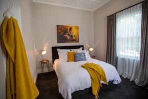 a bedroom with a bed with a yellow blanket on it at Coghill Cottage in Whitianga