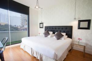 a bed room with a white bedspread and a large window at Ife Boutique in Lima