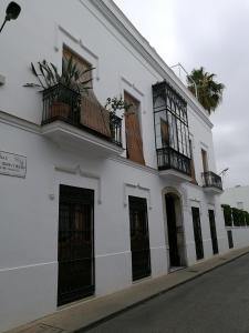 een wit gebouw met balkons aan een straat bij Apartamento Aldama en el centro de Sanlúcar de Barrameda in Sanlúcar de Barrameda