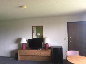 a room with a tv and a dresser with a mirror at Prairie Rose inn in Edgeley