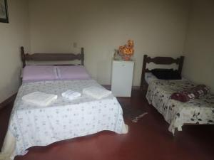 Pousada Sitio da Serra في كارانكاس: غرفة نوم بسريرين وخزانة فيها