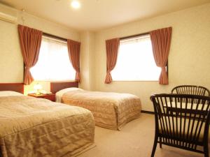 Habitación de hotel con 2 camas y 2 sillas en Akakura Yours Inn, en Myoko