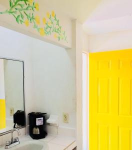 ein Bad mit gelber Tür und Waschbecken in der Unterkunft Hotel y R.V. Park El Moro in Loreto