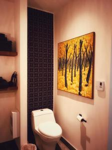 uma casa de banho com WC e uma pintura na parede em La Ruelle Hébergement em Saint-Siméon