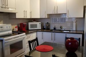 cocina con armarios blancos y mesa con taburete rojo en 2-Bedroom Apartment #30A by Amazing Property Rentals, en Gatineau