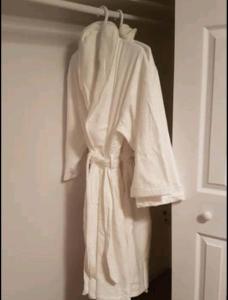 a white robe hanging on a rack in a closet at 2-Bedroom Apartment #30A by Amazing Property Rentals in Gatineau