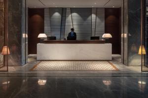 a person sitting at a reception desk in a lobby at Leshan Ramada Hotel in Leshan