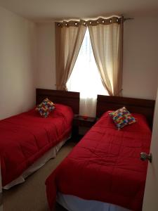 1 dormitorio con 2 camas con sábanas rojas y ventana en PUQ Rent Apartment, en La Serena