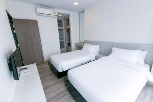 una camera d'albergo con due letti e una televisione di Locals Prio ChiangMai Central Airport Plaza a Chiang Mai Altre 74 foto