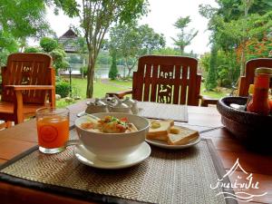 stół z miską jedzenia, chleba i drinka w obiekcie Baan Nam Pen Resort w mieście Amphawa