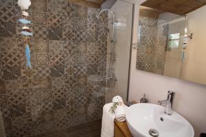 uma casa de banho com um lavatório e um chuveiro com um espelho. em ARISTIDIS'S PLOUTI MOIRES em Ploutí