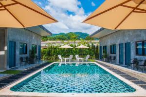a swimming pool with chairs and umbrellas at Ongsa House in Bang Tao Beach