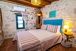 a bedroom with a bed in a room with stone walls at ARISTIDIS'S PLOUTI MOIRES in Ploutí