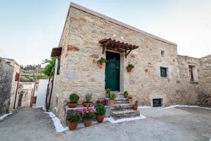 a stone building with a green door and potted plants at ARISTIDIS'S PLOUTI MOIRES in Ploutí