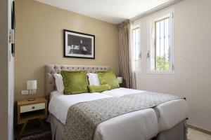 a bedroom with a large white bed with green pillows at The Sephardic House Hotel in The Jewish Quarter in Jerusalem