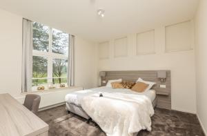 biała sypialnia z łóżkiem i oknem w obiekcie Fletcher Kloosterhotel Willibrordhaeghe w mieście Deurne