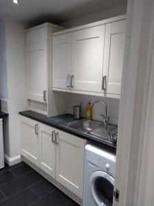 eine weiße Küche mit einem Waschbecken und einer Waschmaschine in der Unterkunft Clifton Apartment in Luton