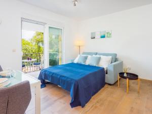 sypialnia z niebieskim łóżkiem i balkonem w obiekcie Appartments Adriatic w mieście Omišalj