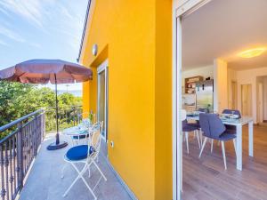 balkon ze stołem, krzesłami i parasolem w obiekcie Appartments Adriatic w mieście Omišalj