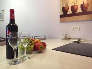 a bottle of wine and a bowl of fruit on a kitchen counter at Ezore Yam Apartments - Ben Gurion 99 in Bat Yam