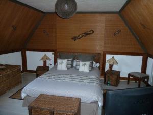 1 dormitorio con 1 cama grande y paredes de madera en Les Alicourts, en Annebault