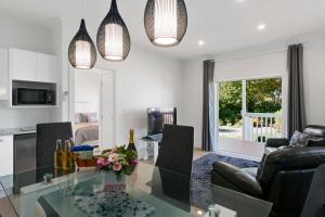 cocina y sala de estar con mesa de cristal en The Retreat Luxury Garden Villa, en Taupo