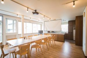 a large room with a table and chairs and a projection screen at Hostel KIKO in Sendai