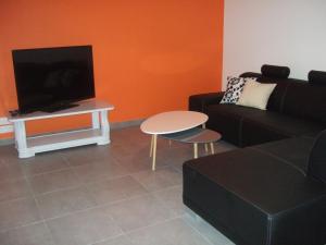 a living room with a couch and a table and a tv at Gite Les Gobelins in Paimpont