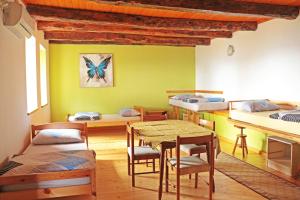 ein Zimmer mit mehreren Betten, einem Tisch und Stühlen in der Unterkunft Stonehouse in Nova Gorica