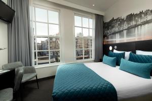 a hotel room with a bed and a desk and windows at Singel Hotel Amsterdam in Amsterdam
