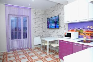 クラスノダールにあるПремиум апартаменты в центре Краснодараのキッチン(紫色のキャビネット、電子レンジ付きテーブル付)