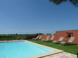 una piscina con sedie a sdraio di Gites et Roulottes Du Grand Puits a Saint-Laurent-dʼAigouze