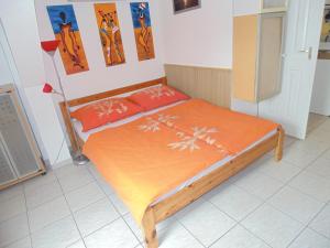 un letto con lenzuola arancioni e cuscini arancioni in una stanza di Álmos Apartman a Siófok