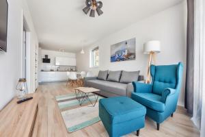uma sala de estar com um sofá e uma cadeira azul em Apartamenty Sun&Snow Osiedle Bursztynowe em Kolobrzeg