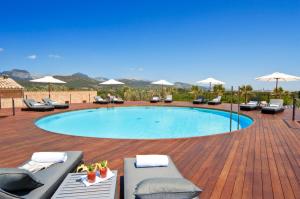 una piscina en una terraza de madera con sillas y sombrillas en Sa Cabana Hotel & Spa - Adults Only en Consell