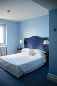 a blue bedroom with a bed with white sheets and pillows at Hotel Riviera & Maximilian's in Trieste