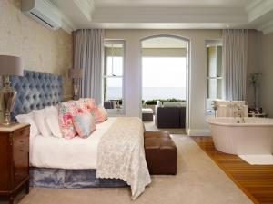 Schlafzimmer mit einem Bett, einer Badewanne und einer Badewanne in der Unterkunft 21 Nettleton Boutique Hotel & Luxury Residence in Kapstadt