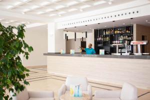 a man standing at the counter of a bar at Grupotel Club Menorca in Son Xoriguer