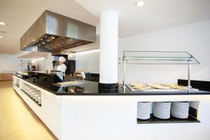 a kitchen with a person preparing food in a kitchen at Grupotel Club Menorca in Son Xoriguer