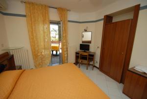 a bedroom with a bed and a desk with a computer at Hotel Baia Del Sorriso in Castiglioncello