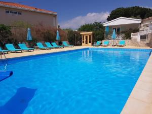 a large swimming pool with blue chairs and umbrellas at Villa Colombier in Fréjus