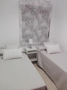 サンルーカル・デ・バラメダにあるApartamento ateneoのベッドルーム1室(ベッド2台、ランプ付きテーブル付)