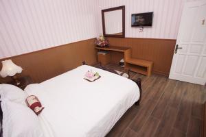 Schlafzimmer mit einem weißen Bett und einem Spiegel in der Unterkunft Huis Van Gustafine Floor 2 in Malang